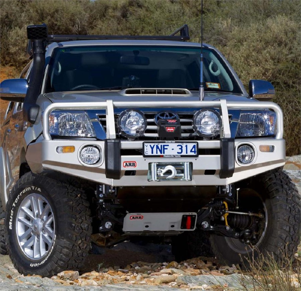 An ARB Toyota Hilux SUV with steel components is parked on a rocky area.