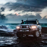 An Old Man Emu Toyota Land Cruiser, featuring Old Man Emu coil springs for enhanced suspension, parked on a scenic rocky beach. The vehicle showcases oxidation protection to ensure durability and an easy installation process.