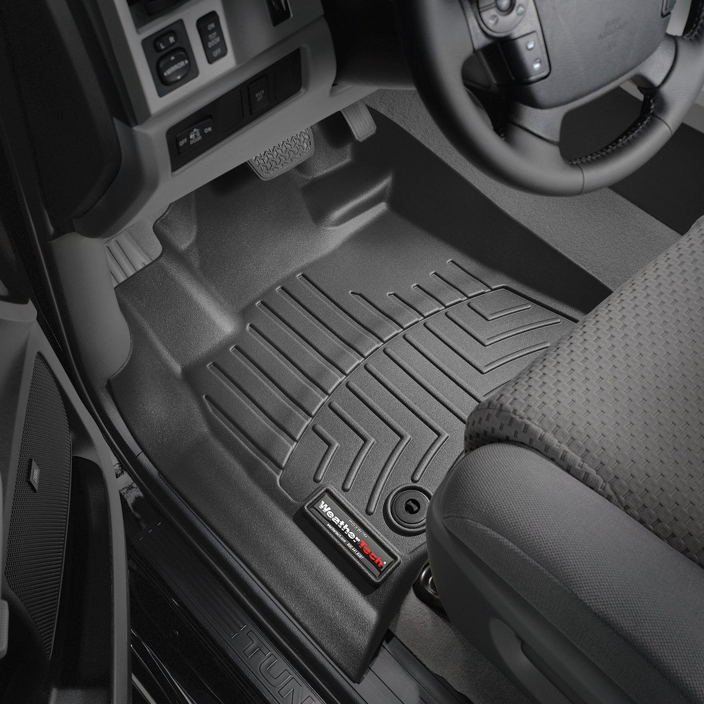 The interior of a car featuring Weathertech DigitalFit 1st Row Floor Liners for Toyota Tundra (2014-2021) and a steering wheel.