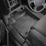 The interior of a car featuring Weathertech DigitalFit 1st Row Floor Liners for Toyota Tundra (2014-2021) and a steering wheel.
