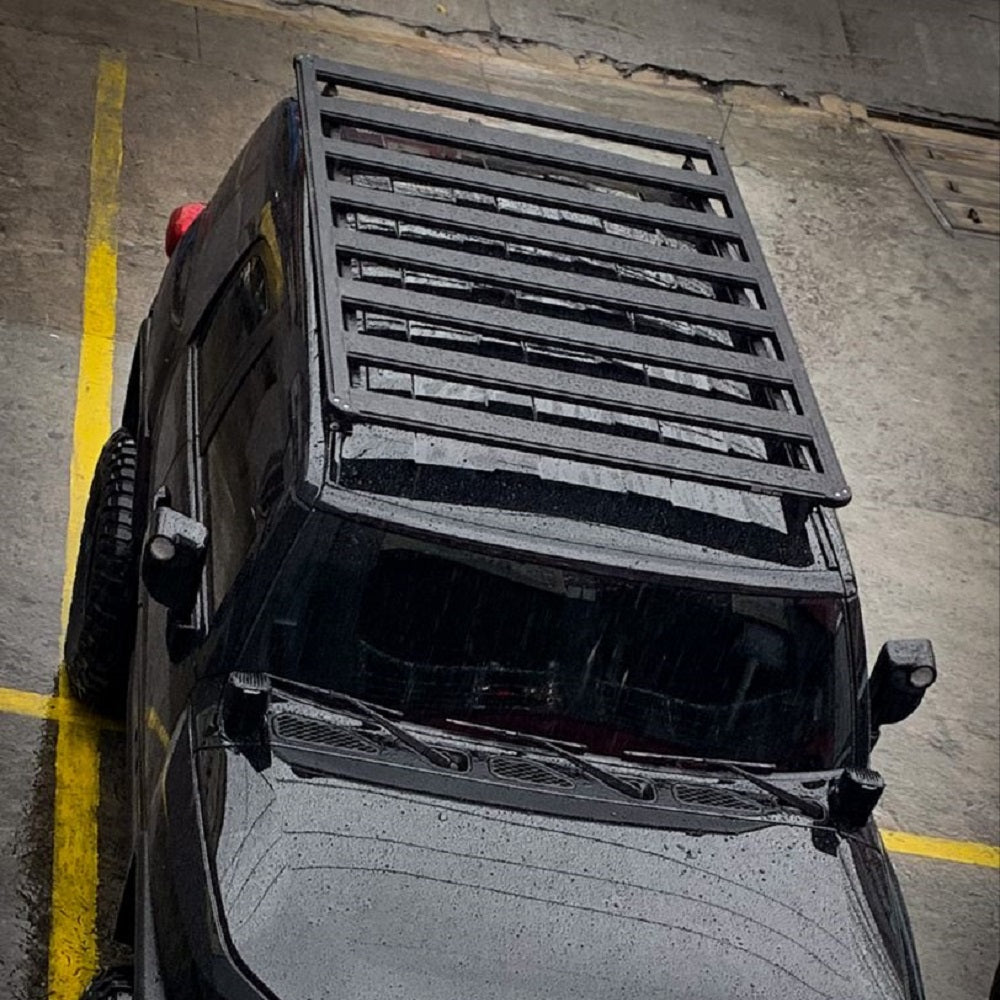 A black jeep wrangler with a Base Rack For Toyota FJ Cruiser 2007-2016 ARB 1770040 is parked in a parking lot.