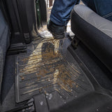 A person is standing in the back seat of a vehicle, experiencing extreme weather conditions with the Weathertech Floorliner HP 2nd Row Floor Mats for Toyota Tacoma 2018-ON (Double Cab Models) from Weathertech.