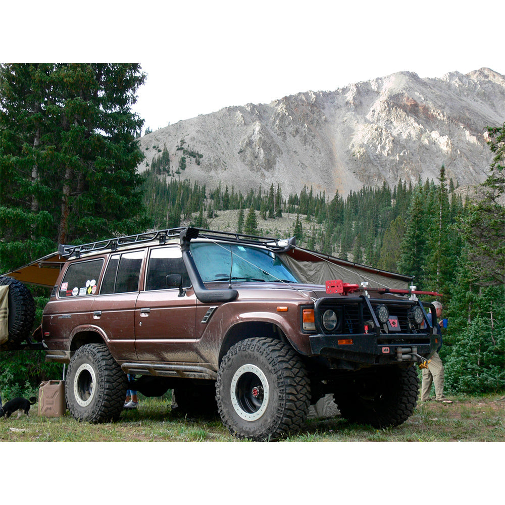An Old Man Emu Toyota Land Cruiser parked next to a mountain, showcasing its impressive suspension performance.