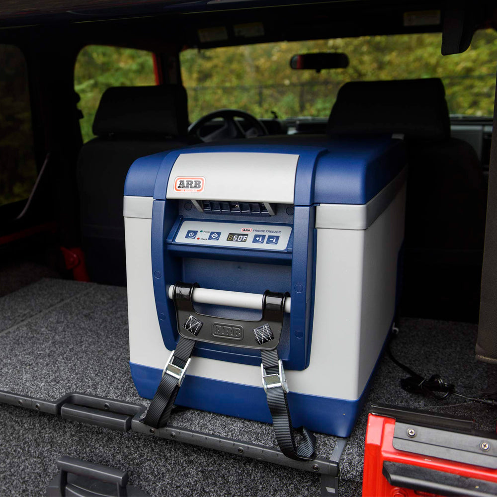 An ARB Fridge Freezer 82 Qt 10800782, perfect for your outdoor adventures, securely stored in the back of a jeep.