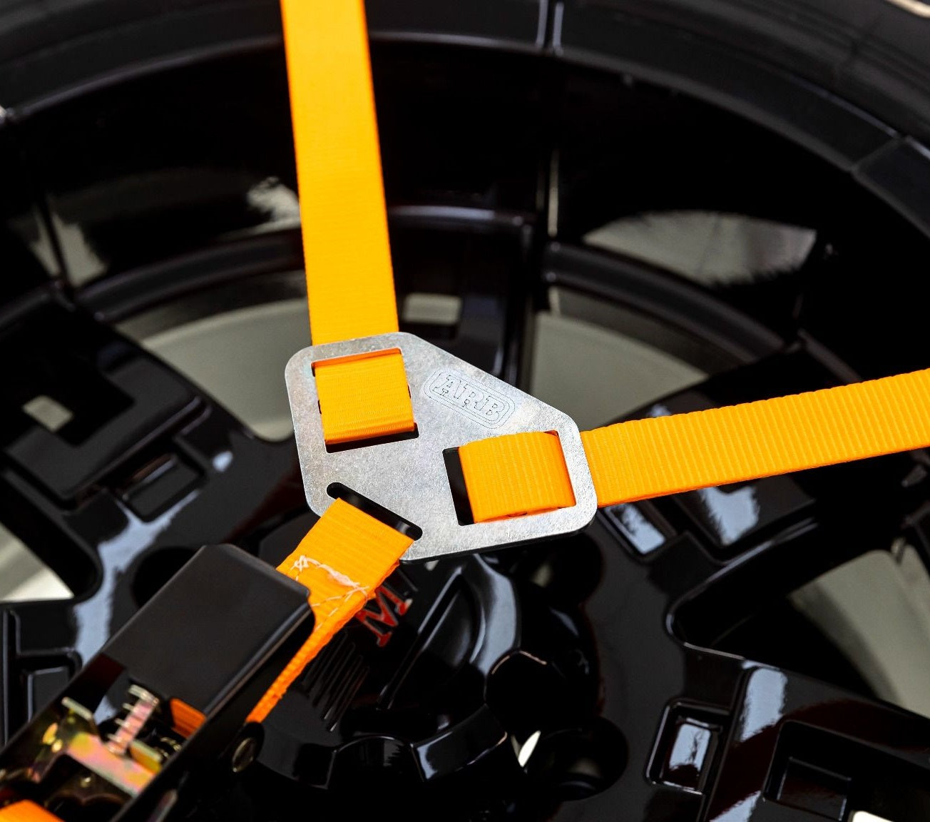 A close up of an ARB Rack Spare Wheel Y Strap 1780380 attached to a tire, showcasing tie-down points for cargo loading on the BASE Rack.