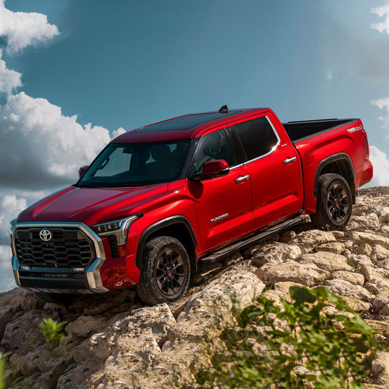 The 2020 Toyota Tacoma equipped with the Old Man Emu BP-51 Fit Kit Front VM80010034 showcases impressive suspension systems and shock absorbers as it conquers a rocky hill, delivering an exceptional ride quality.
