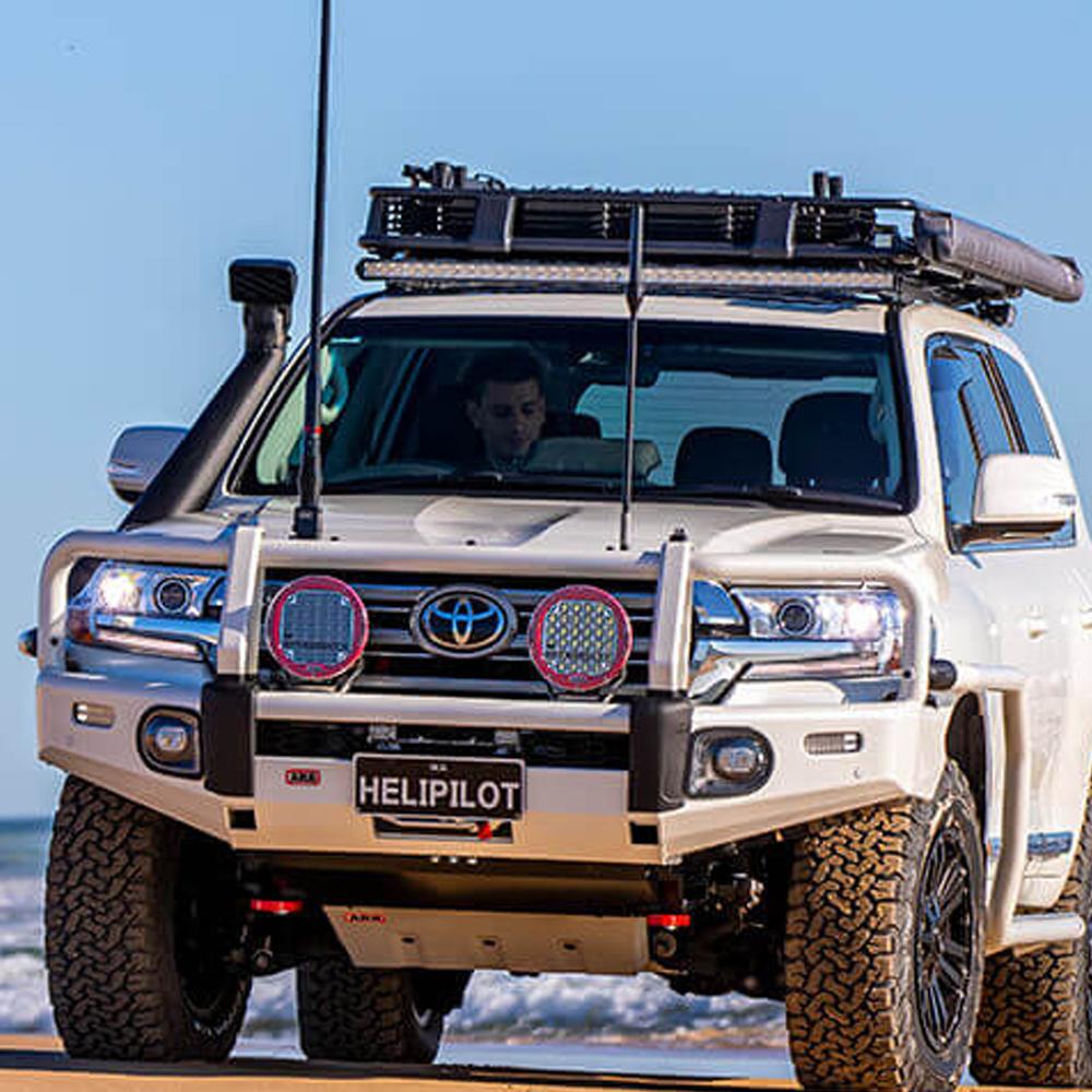 A white ARB Alloy Flat Rack With Mesh 87”X 44” for Toyota Land Cruiser 200 Series 2008 - 2020 is parked on the beach.