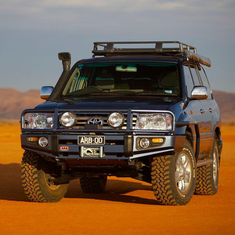 An ARB Roof Rack Fitting Kit 70” X 49” for Toyota Land Cruiser 120 Series ARB 3721020 is parked in the desert, providing secure storage for adventure gear with its fitting kit.