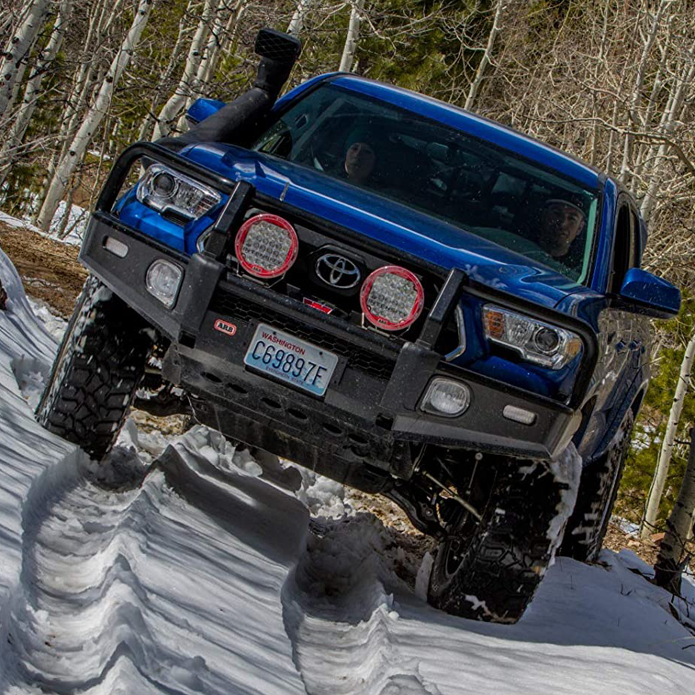 An air bag compatible ARB Summit Bumper for Toyota Tacoma 2016-2022 is driving through the snow.