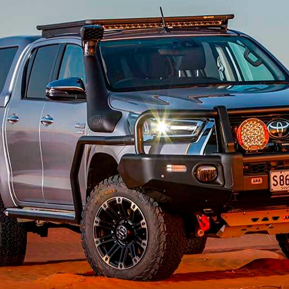 The ARB Alloy Flat Rack 70” X 44” with Mesh Floor for Toyota Land Cruiser 100 Series 1997-2007 is parked in the desert, ensuring secure storage.