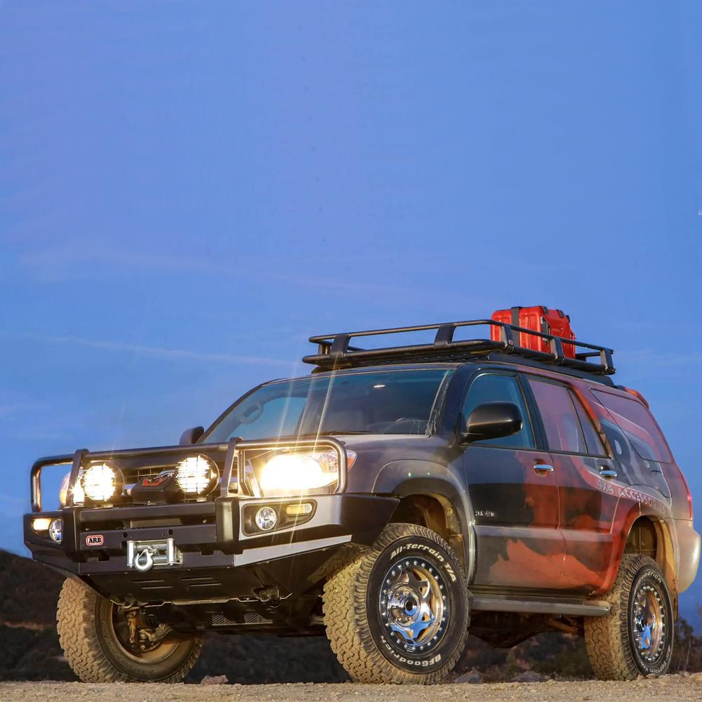 An ARB SUV with the Alloy Roof Rack Basket 87” X 49” ARB 4900010M on top of it driving down a dirt road.
