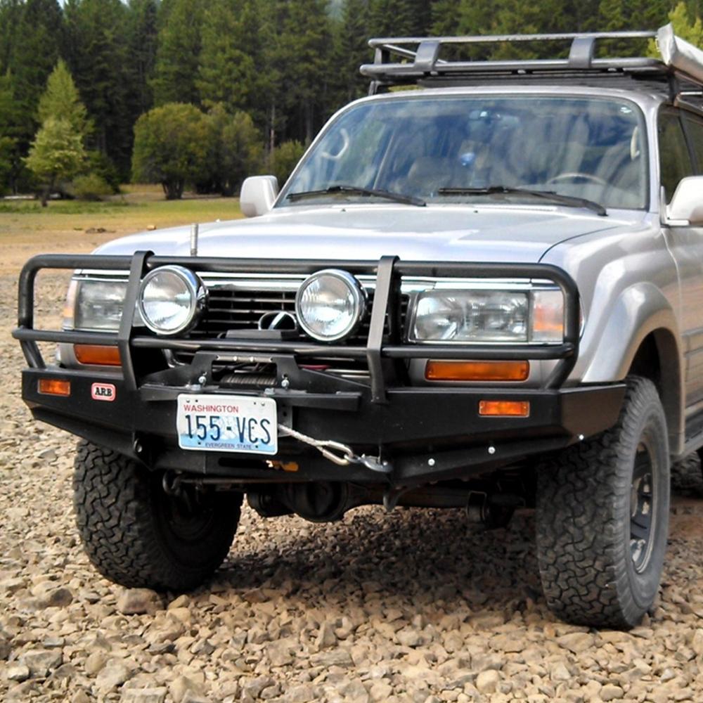 A silver Toyota Land Cruiser is parked on a dirt road, providing secure storage while equipped with an ARB Steel Rack with Mesh Floor 43” X 49" for Jeep Cherokee XJ ARB 3800030MK for optimal functionality.
