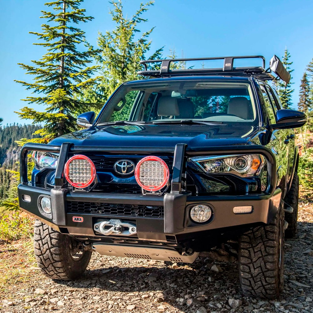 A black ARB Touring Roof Rack FJ Cruiser (2007-2009) 3800200KLC2 parked on a dirt road with a roof rack for increased vehicle's load capacity.