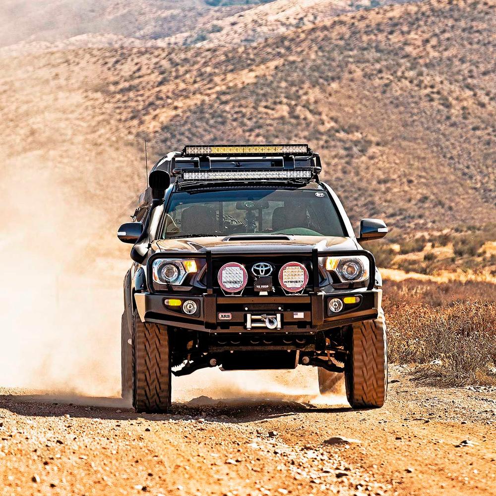 An ARB Old Man Emu Front Nitrocharger Sport Strut 90016 for Toyota Prado 150 Series SWB with compression valving is driving down a dirt road.