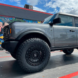 A gray truck with Old Man Emu ARB Trim Packer Kit FK111 for Ford Bronco (21-ON) is parked in front of a graffiti wall.
