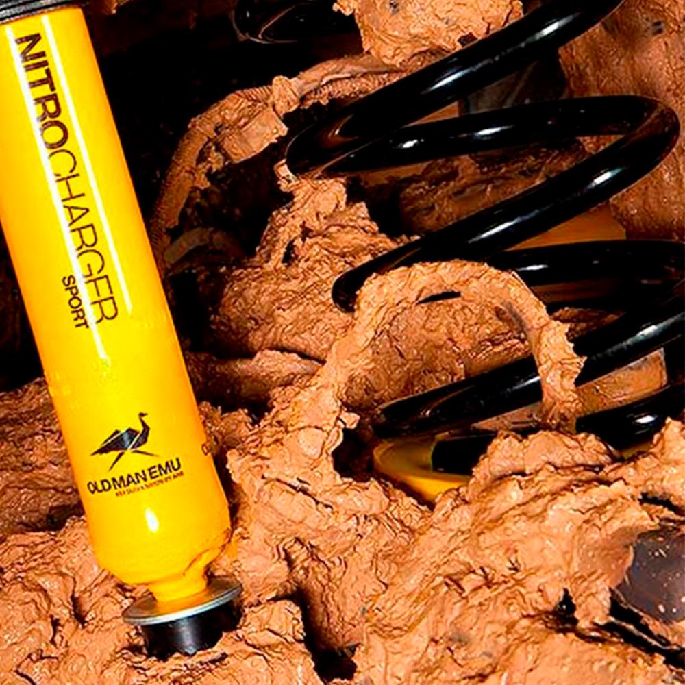 An Old Man Emu yellow shock absorber featuring lift, sitting in a pile of dirt.