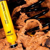 An Old Man Emu yellow shock absorber featuring lift, sitting in a pile of dirt.