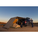 A man is setting up a tent with awning walls on the back of a SUV using the ARB Touring 3 Wall Set No Floor 813206 from ARB.