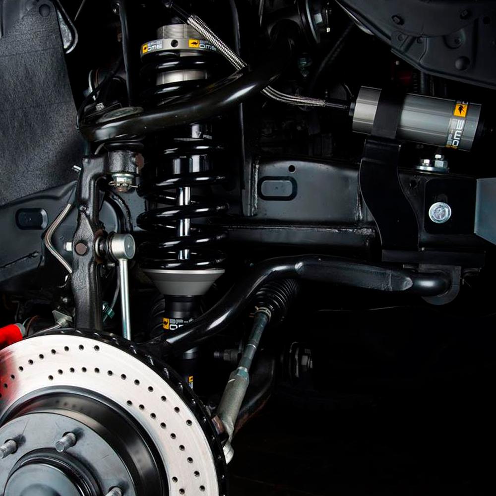 A close up of a vehicle's suspension system featuring an OME BP-51 Front Coil Over LH BP5190010L for Toyota Tundra (2007-2022) Old Man Emu coil and high-temperature hose.