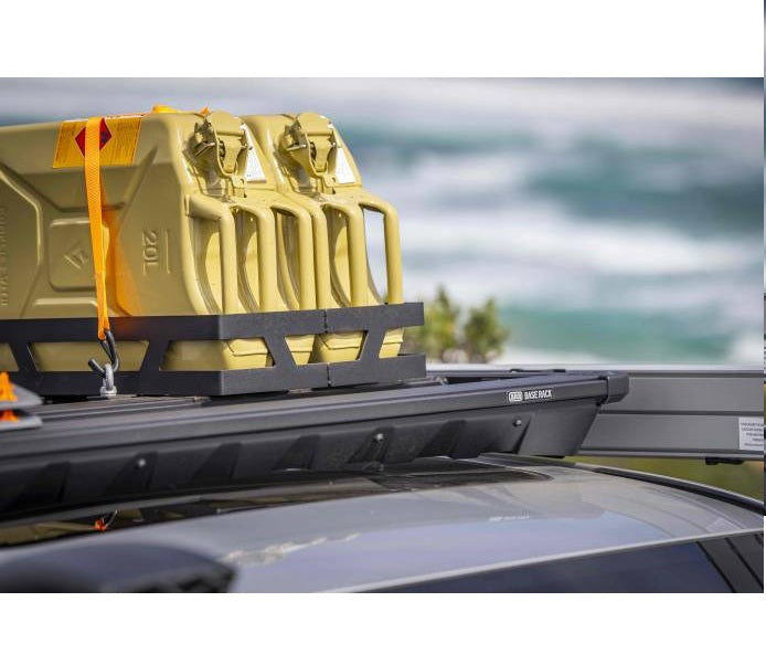 A car equipped with the BASE Rack, featuring a dovetail system and two yellow ARB Eye Bolt Tie-Down (Set Of Four) 1780200 cans secured with eyebolt tie-downs on top.