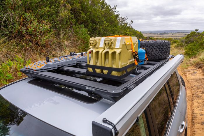 A Land Rover with an ARB BASE Rack Awning Bracket 1780240 by ARB and a roof rack on top of it.
