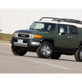 A green SUV with an ARB Base Rack Mount Kit (Black) For Toyota FJ Cruiser (2007-2016) ARB 17920020 parked in a parking lot.