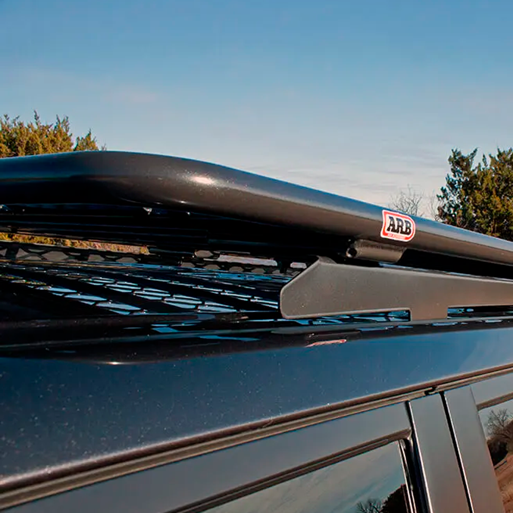 A black SUV with an ARB Steel Basket Rack With Mesh Floor 87" X 44" on top.