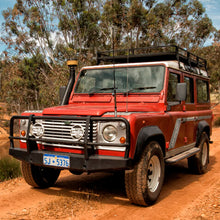 Load image into Gallery viewer, An OME 2 inch Lift Kit for Land Rover Defender 110 (85-17)-equipped Old Man Emu land rover parked on a dirt road.