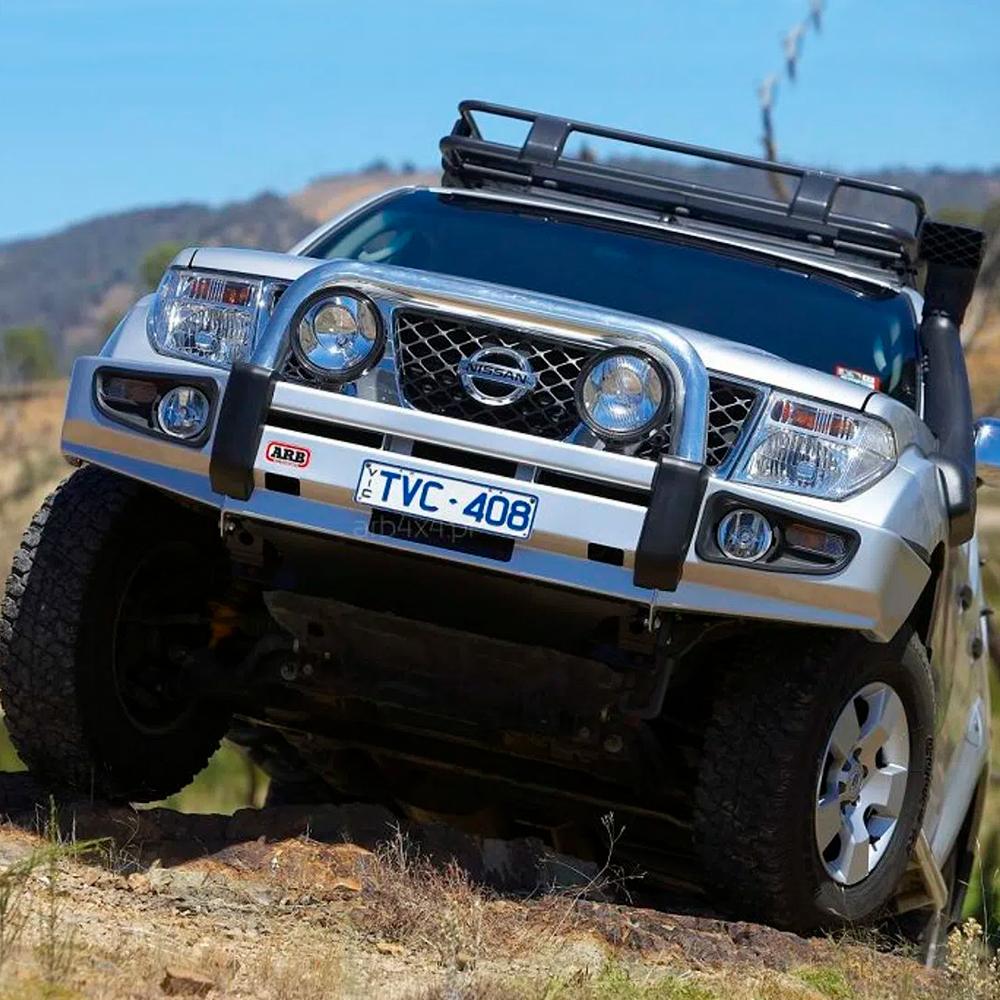 A silver Nissan Navara with secure storage and an ARB Roof Rack Fitting Kit for Nissan Pathfinder and NAVARA D40 ARB 3738010 is driving down a hill.