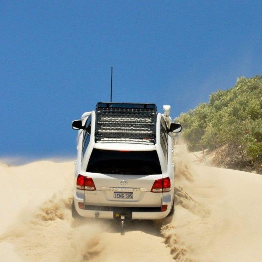 An ARB Alloy Flat Rack With Mesh 87”X 44” for Toyota Land Cruiser 200 Series 2008 - 2020 driving through a sand dune.