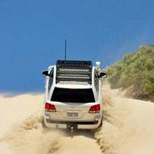 Load image into Gallery viewer, An ARB Alloy Flat Rack With Mesh 87”X 44” for Toyota Land Cruiser 200 Series 2008 - 2020 driving through a sand dune.