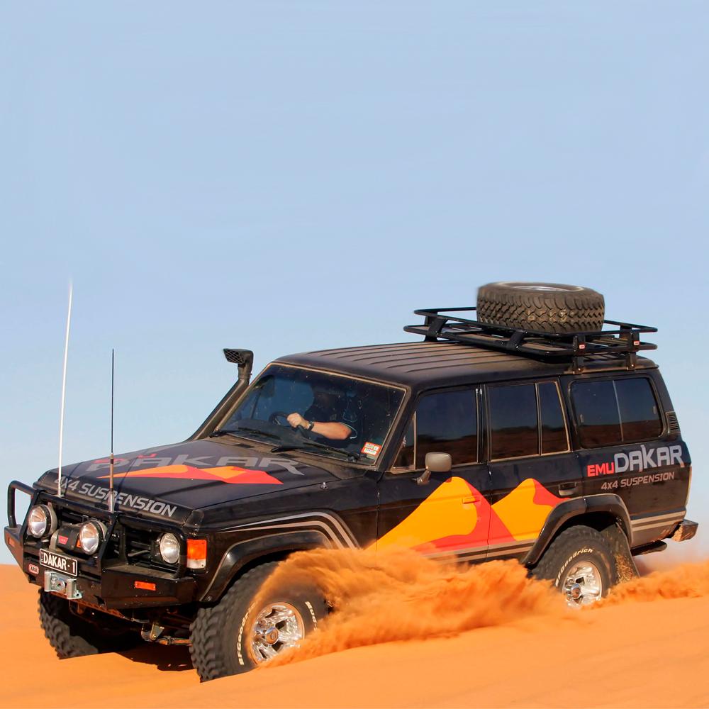 An ARB Roof Rack Fitting Kit 43” x 49” for Toyota Land Cruiser 1980 - 1990 ARB 3700040 equipped with a secure storage system drives through the desert.