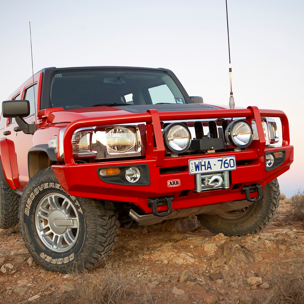 A red jeep parked on a dirt road, equipped with an ARB Roof Rack Fitting Kit for Toyota Land Cruiser 200 Series ARB 3715010 for high capacity.
