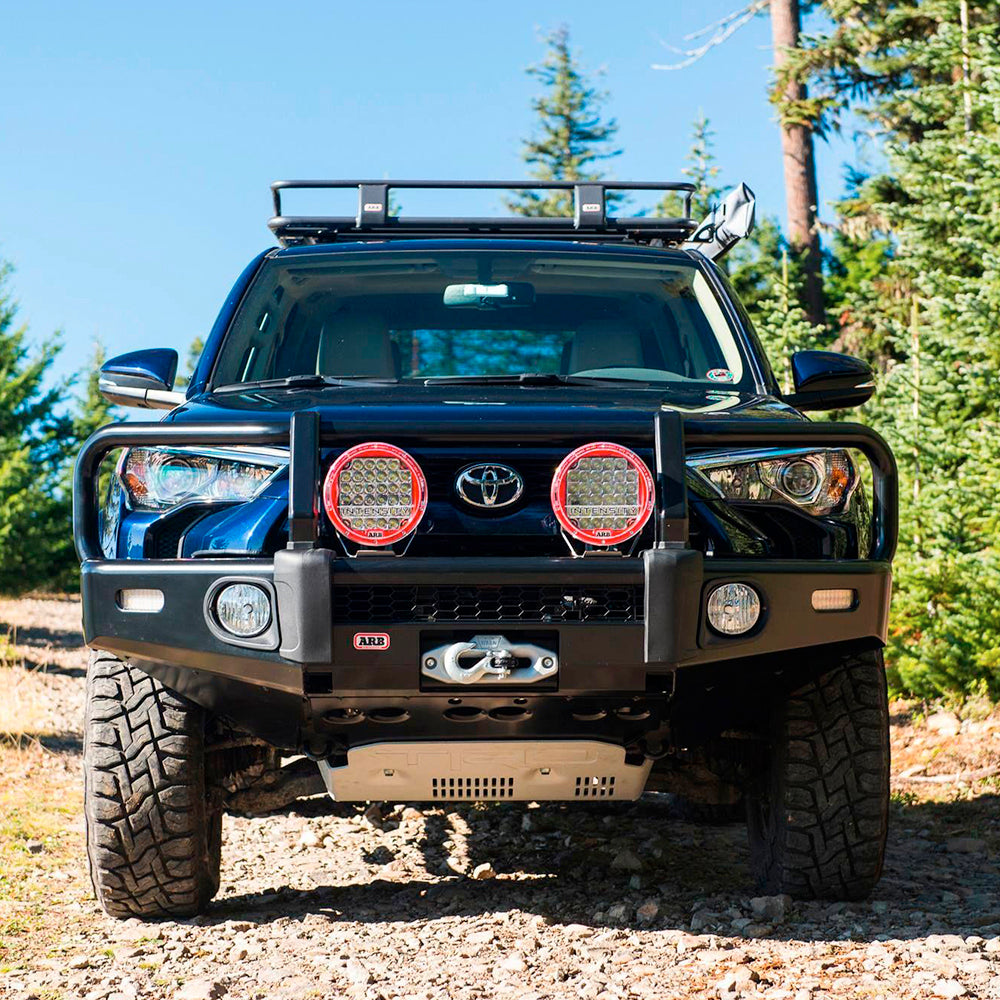 A black ARB 17921030 Toyota 4Runner with a Base Rack Mount Kit (Black) For Toyota 4Runner (2010-2022) is parked on a dirt road.