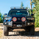 A black ARB 17921030 Toyota 4Runner with a Base Rack Mount Kit (Black) For Toyota 4Runner (2010-2022) is parked on a dirt road.
