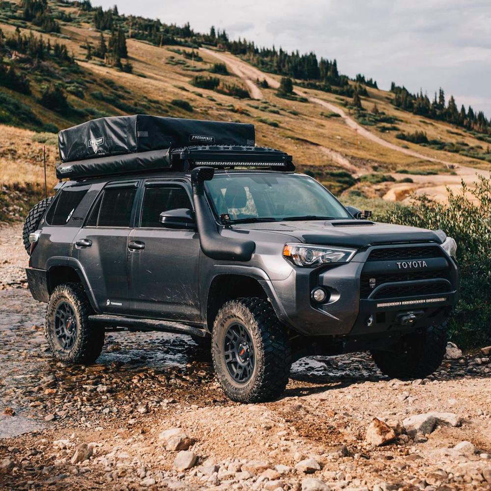 The Old Man Emu Rear Coil Springs 2895 for Toyota Prado 150 & 120 Series, 4Runner, FJ Cruiser, Hilux, known for their impressive ride height and off-roading capabilities, are securely parked in a rocky area.