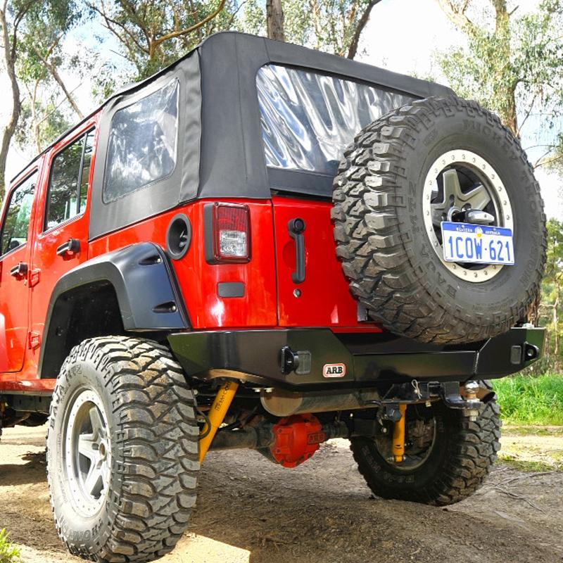 A red Old Man Emu jeep parked on a dirt road, equipped with the ARB Old Man Emu Rear Nitrocharger Sport Shock 60067L for Jeep Wrangler JL.