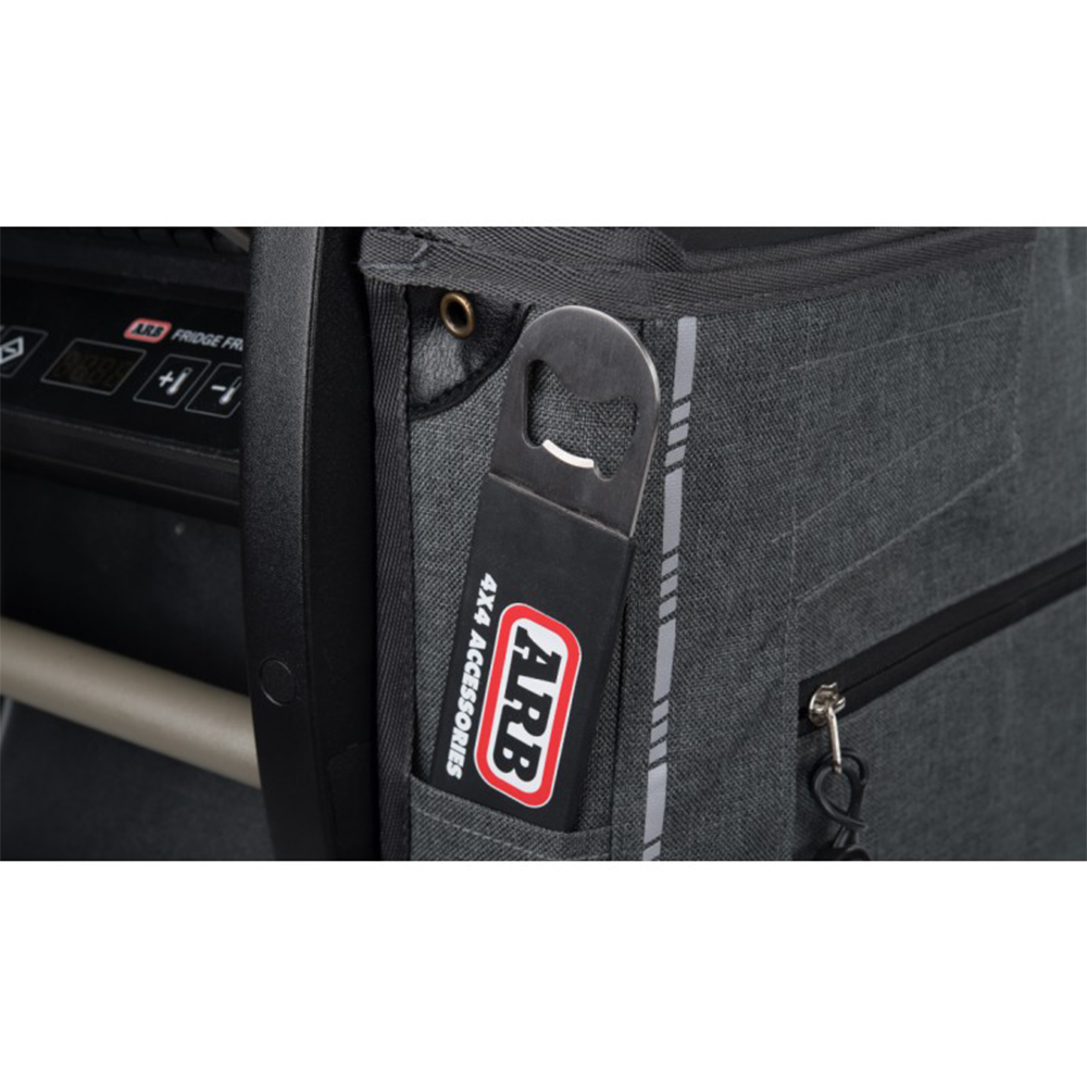 An ARB Protective Cover Transit Bag Canvas for 50 Quarts ARB Fridge Freezers 10900013 with a bottle opener attached to it, designed to protect and transport cold items like bottles in a convenient gray bag.