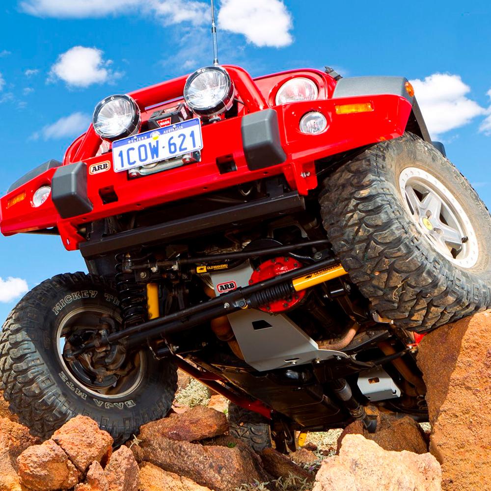 A red Jeep with Old Man Emu Rear Coil Springs 2889 for Toyota Prado 150 Series -1.5 inch Estimated Lift (LWB MODELS) on rocks, offering easy installation and ride height increases.