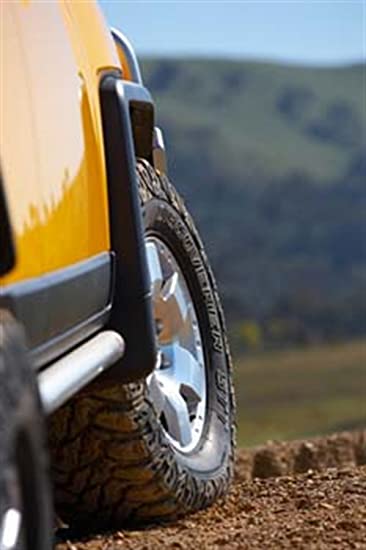A yellow FJ Cruiser truck is parked on a dirt road, equipped with Deluxe Rock Rails ARB 4420100 rock sliders by ARB.