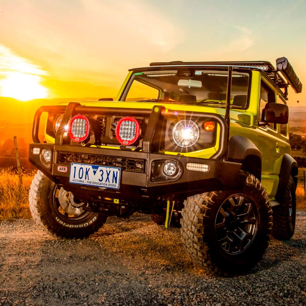 A yellow Old Man Emu jeep with oxidation protection parked on a dirt road at sunset.