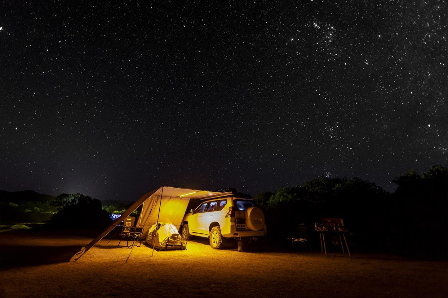 A waterproof ARB camper van under a starry sky with an ARB Touring Aluminum Awning with Light 814411.