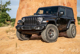 A black Fox Racing Jeep Wrangler JL 2 Door with larger tires parked in front of a rock formation.