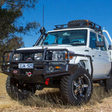 A white Toyota ARB truck securely parked in a grassy field, with an ARB Steel Roof Rack Basket with Mesh Floor ready for drainage channel installation.