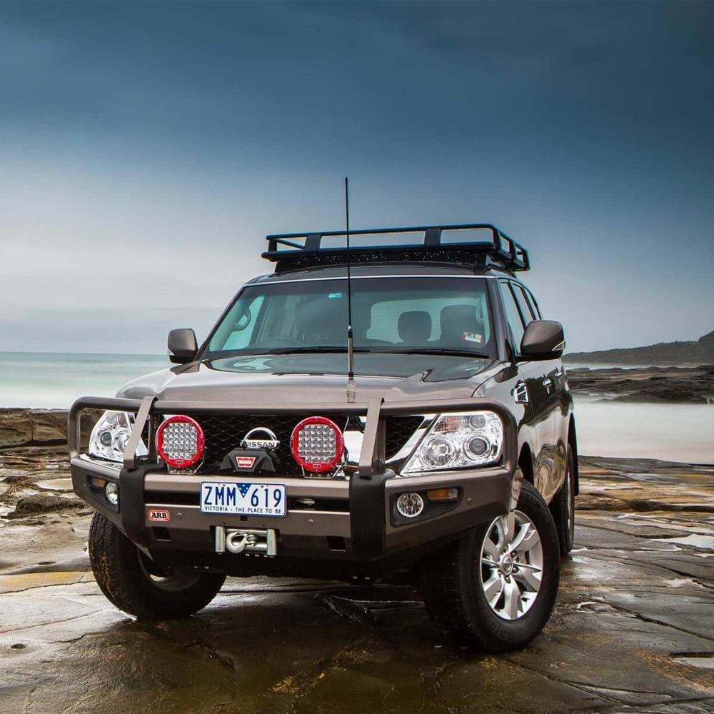 A Nissan Patrol parked on a rocky beach with an ARB Roof Rack Mounting Kit for NISSAN and Toyota Land Cruiser 3700100.