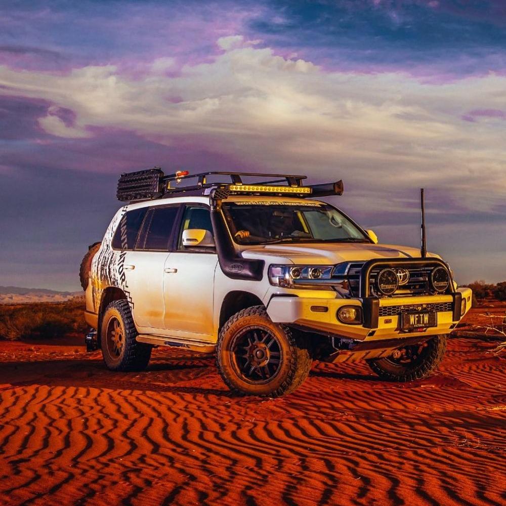A durable white ARB Alloy Flat Rack With Mesh 87”X 44” for Toyota Land Cruiser 200 Series 2008 - 2020 parked in the desert, providing maximum protection through its steel construction.