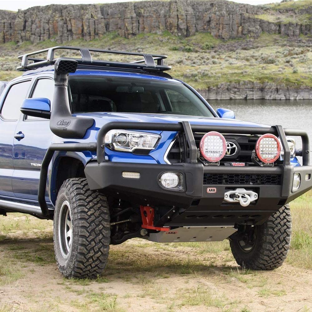 A high capacity blue ARB Toyota Tacoma with secure storage is parked next to a lake.