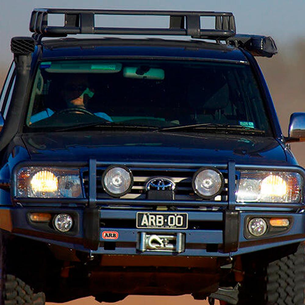 An ARB Roof Rack Fitting Kit 70” X 49” for Toyota Land Cruiser 120 Series ARB 3721020 driving down a dirt road, offering secure storage options with its fitting kit.