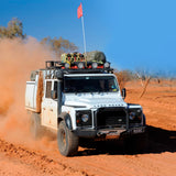 A white Land Rover with exceptional ground clearance is driving through the desert, equipped with the OME 2 inch Lift Kit for Land Rover Defender 110 (85-17) by Old Man Emu.