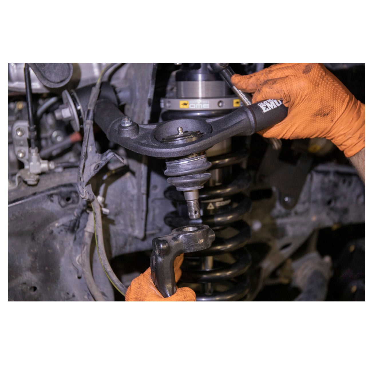 A person is working on the OME Front Upper Control Arms for Toyota Hilux (2005-2022) UCA0003 of Old Man Emu suspension.